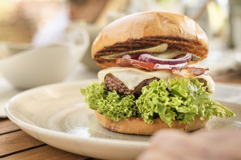 ein gefüllter Brioche Burger auf einem Gartentisch im Sommer