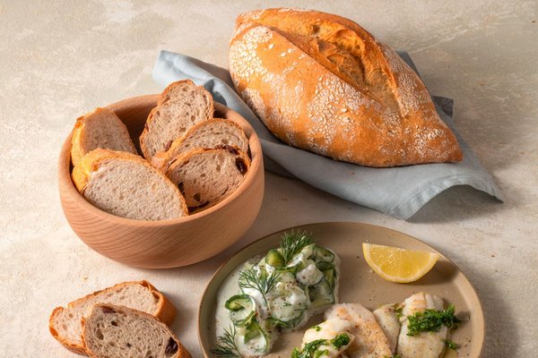 Brotscheiben, dazu Fischfilets und Gurkensalat mit Dill und Zitrone.