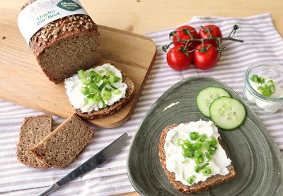 Haubis Bio-Dinkelvollkornbrot auf einem Teller mit Aufstrich und Gurken serviert