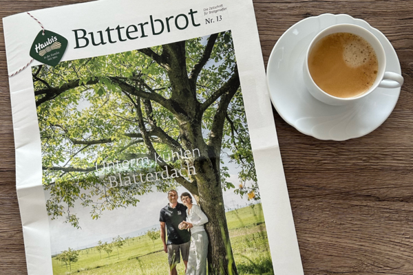 Kundenmagazin Butterbrot liegt auf einem Tisch mit einer Tasse Kaffee daneben