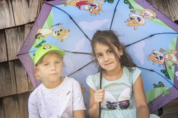 Kinder die unter einen Haubis-Regenschirm sitzen