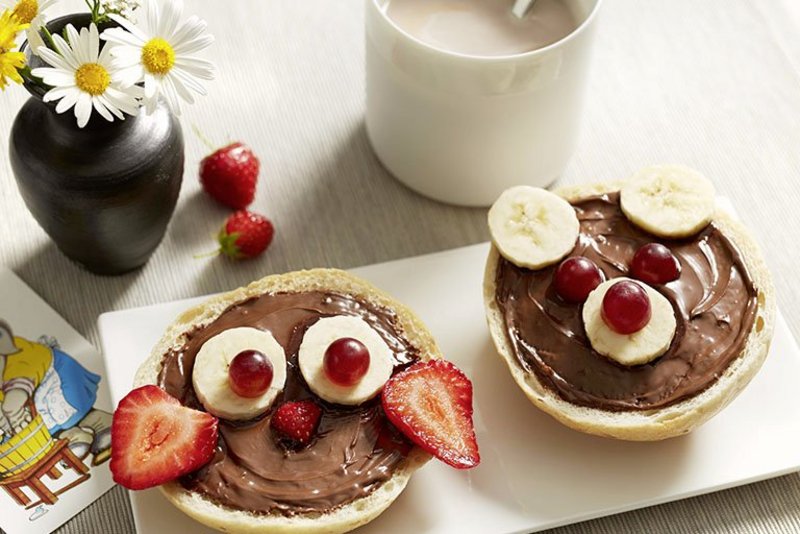 Nutellasemmel mit Früchten garniert auf einem weißen Teller mit Deko