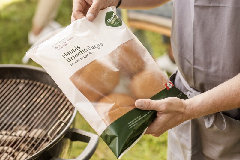 Brioche Burger in der Verpackung welche gerade ausgepackt wird