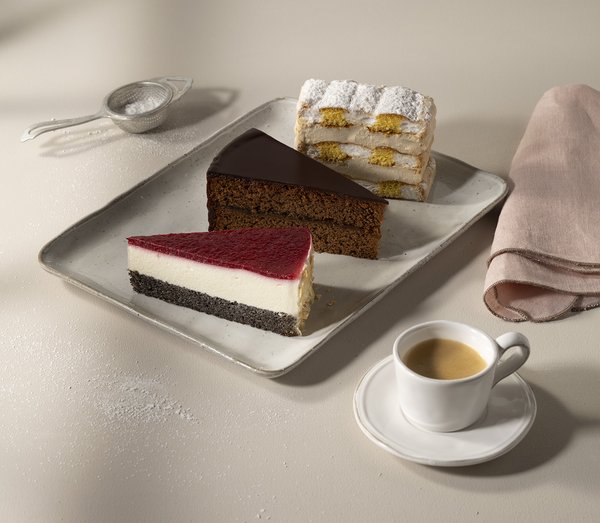 Haubis Sachertorte, Mohntorte und Kardinalschnitte auf einem Teller mit Kaffee