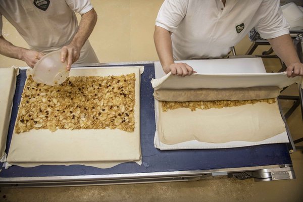 Apfelstrudel am Blech welcher gerade in der Konditorei eingerollt wird 