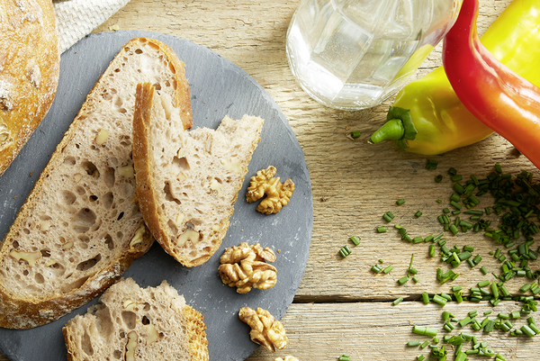 Haubis Walnussbrot aufgeschnitten auf einem Teller mit Paprika und Schnittlauch