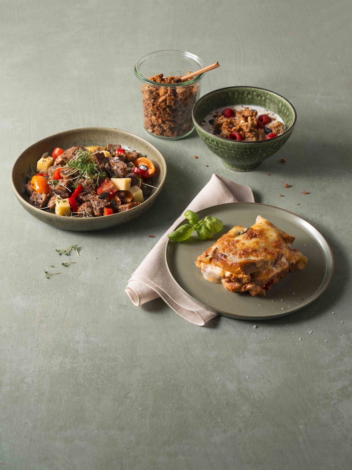 Knuspermüsli, Brotlasagne, Brotsalat auf Teller auf einem grauen Tisch